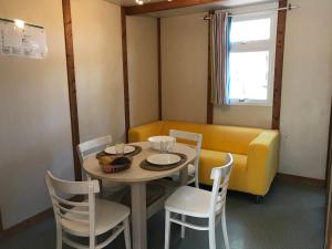 ein Esszimmer mit einem Tisch und Stühlen sowie einem gelben Sofa in der Unterkunft Odeceixe Bungalow-Parque de Campismo Sao Miguel in Odeceixe + 59 Fotos