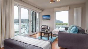 a living room with a bed and a couch and windows at Castle Penthouse in Deganwy