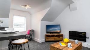 a living room with a television and a table at Station Loft in Deganwy