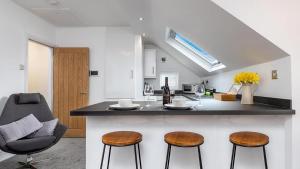 a kitchen with a counter and two stools at Station Loft in Deganwy +10 photos