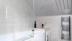 a white bathroom with a bottle of wine on a shelf at Station Loft in Deganwy