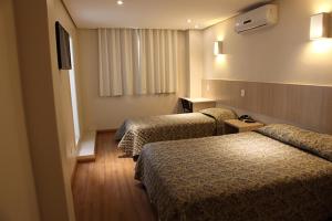 a hotel room with two beds and a television at Golden Hotel - O MAIS CENTRAL - Pet Friendly in Chapecó
