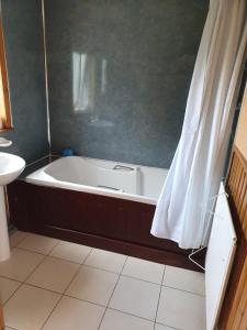 y baño con bañera y lavamanos. en RoSE COTTAGE THREE BEDROOM HOUSE WITH PARKING, en Carsphairn