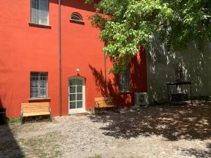 two benches sitting in front of a red building at La Meridiana in Piacenza