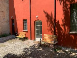 dwie ławki siedzące przed czerwonym budynkiem w obiekcie La Meridiana w mieście Piacenza