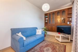 um sofá azul numa sala de estar com uma televisão em Casa vacanze i Mandorli em SantʼAnna Arresi