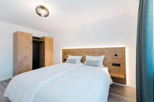 a bedroom with a white bed with a wooden headboard at Moderne 3 Zi.-FeWo BlackForest Art Nähe Freiburg in Simonswald