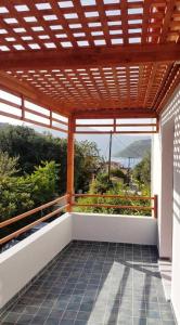 an outdoor balcony with a wooden pergola and a view of a mountain at Aletri & Orgoma in Vathi