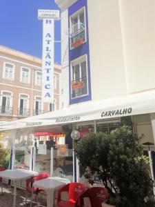 een restaurant met tafels en stoelen voor een gebouw bij Hotel Atlântica in São Martinho do Porto