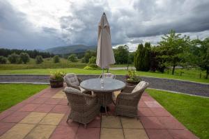 a patio with a table and an umbrella at Springburn Farmhouse in Spean Bridge