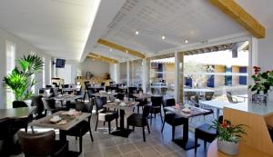 a restaurant with tables and chairs in a room at The Originals City, Hôtel Albizia, Sarlat-la-Canéda in Sarlat-la-Canéda