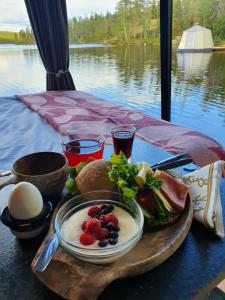 a plate of food on a table with a view of a lake at AuroraHut, Overwater Hut in Kuusamo