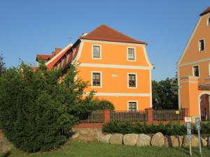 pomarańczowy dom z płotem i drzewem w obiekcie Rittergut zu Groitzsch w mieście Jesewitz