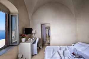 a bedroom with a bed and a window at Mythical Blue Luxury Suites in Fira