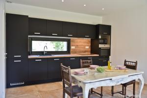 a kitchen with black cabinets and a table with chairs at Casa di Neshama Ghjiseppu in Saint-Florent