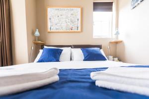 uma cama com lençóis azuis e brancos e almofadas azuis em Belgravia Rooms Hotel em Londres