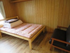 a small bed in a room with a wooden floor at Mizu no Gakko in Shari