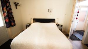 een slaapkamer met een bed met een witte sprei bij Rumah Senang in Den Helder