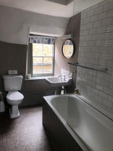a bathroom with a tub and a toilet and a sink at The Golden Pheasant Hotel in Burford