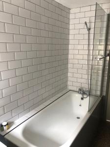 a white tiled bathroom with a tub and a shower at The Golden Pheasant Hotel in Burford