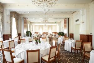 a dining room with white tables and chairs and a chandelier at BRISTOL Hotel Opatija in Opatija