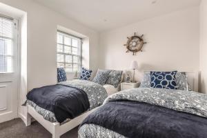 a bedroom with two beds and a clock on the wall at Lime Kiln Cottage, Pentewan, Cornwall in Pentewan