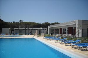 uma piscina com espreguiçadeiras azuis e um edifício em Parque De Campismo Orbitur Guincho em Cascais