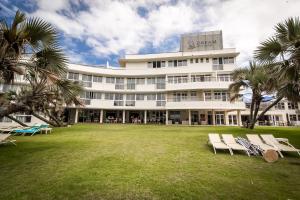 a large white building with chairs and palm trees at Blue Marlin Hotel by Dream Resorts in Scottburgh