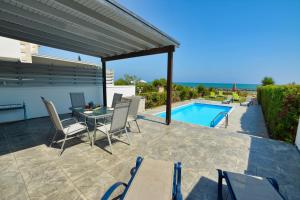 une terrasse avec une table, des chaises et une piscine dans l'établissement Gorgona Villa 14, à Ayia Napa
