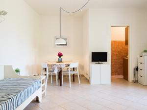 Zimmer mit einem Tisch, einem Bett und einem TV in der Unterkunft La Rotonda Cottages - Klodge in Cala Bitta
