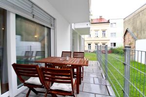 a patio with a wooden table and chairs on a balcony at Spacious Terrace Apt in Modern Klosterneuburg Building in Klosterneuburg