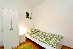 a small white bedroom with a bed and a cabinet at Spacious Terrace Apt in Modern Klosterneuburg Building in Klosterneuburg