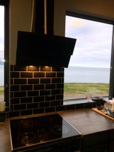 a kitchen with a stove and a large window at Hellnar Ocean View Villa in Hellnar