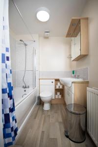 La salle de bains est pourvue de toilettes, d'une baignoire et d'un lavabo. dans l'établissement Lochend Serviced Apartments, à Édimbourg