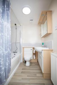 a bathroom with a toilet, sink, and bathtub at Lochend Serviced Apartments in Edinburgh