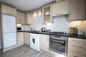 a kitchen with a stove top oven, microwave and refrigerator at Lochend Serviced Apartments in Edinburgh