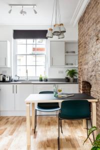 ロンドンにあるBloomsbury By Viridian Apartmentsの白いキャビネット、テーブルと椅子付きのキッチンが備わります。