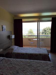 a hotel room with two beds and a large window at Logis Hotel Le Col De L'ange in Draguignan