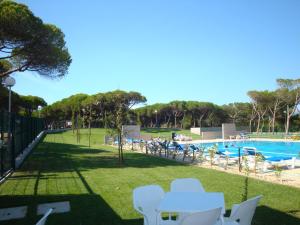 una piscina con tavoli e sedie bianchi in un parco di Parque De Campismo Orbitur Guincho a Cascais