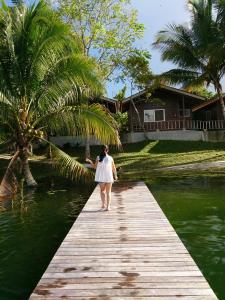 a woman walking on a wooden bridge over the water at Hotel Santa Barbara Tikal in Flores