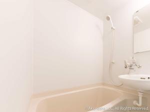 a white bathroom with a sink and a bath tub at Oyado Midokoi in Akune