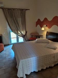 a bedroom with a large bed and a window at Sunrise Hotel Nikiana Lefkada in Nikiana