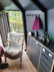 um quarto com uma cadeira, um lavatório e uma janela em AuroraHut, Overwater Hut em Kuusamo