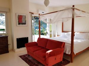 a bedroom with a canopy bed and a red couch at The Lodge Ronda in Ronda