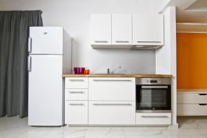 a kitchen with white cabinets and a refrigerator at Cresta Beach Studios in St. Julianʼs