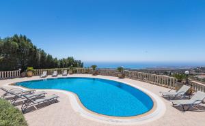 a swimming pool with chairs and a view of the ocean at Resitour - Kamares Village in Paphos