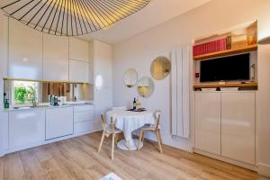 a kitchen with a white table and chairs and a television at GRAND HÔTEL City Center at 2 minutes walk from the beach in Nice