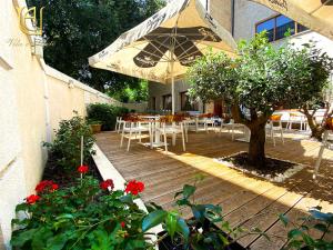 una terrazza in legno con tavoli, sedie e ombrellone di Hotel Vila e Arte City Center a Tirana