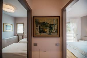 a hallway to a bedroom with two beds and a picture at Casa Chiara in Gardone Riviera