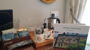 a table with a display of a guest house with cups and a box at Glendon Bed and Breakfast in Matlock